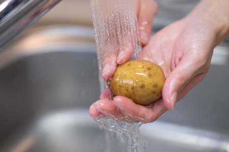 mãos lavando a batata para preparo